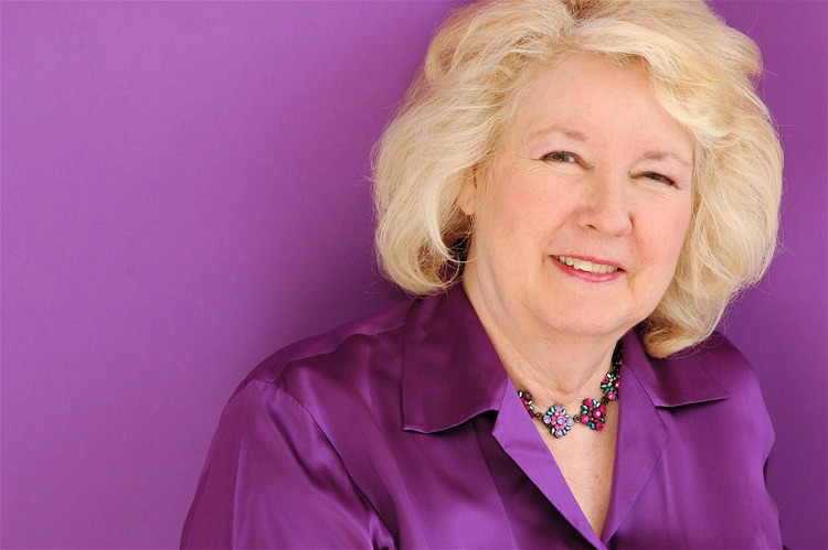 Dr. Faye Snyder, smiling, in a purple blouse against a purple backdrop