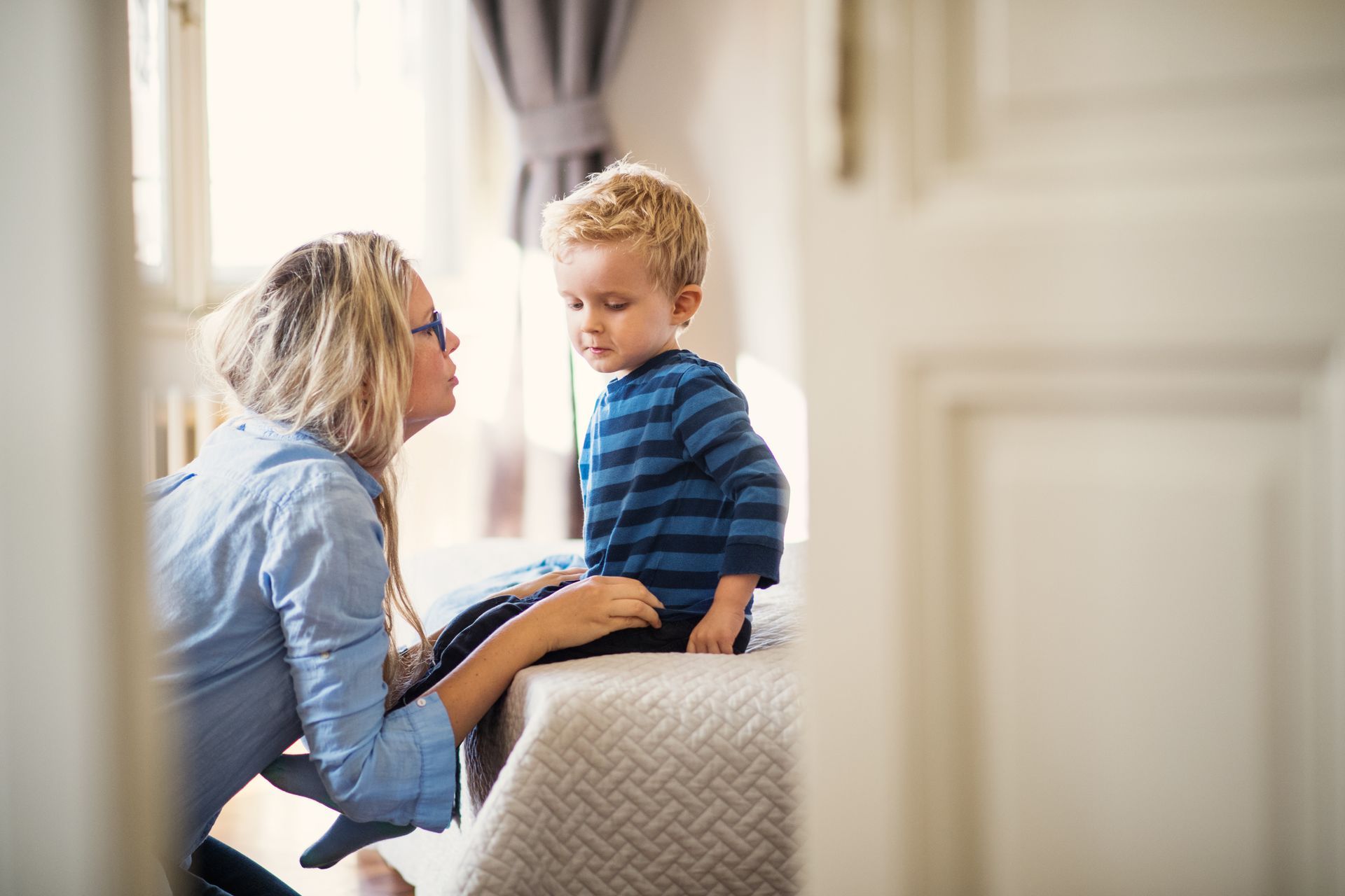 A mother kneeling to talk gently with her young son